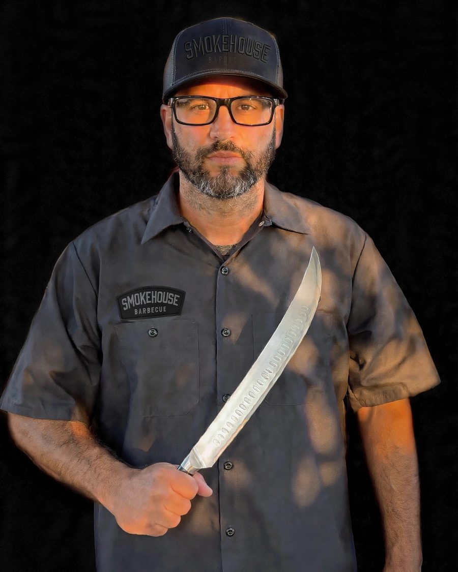 Smokehouse BBQ 305 founder in branded shirt and cap holding a carving knife